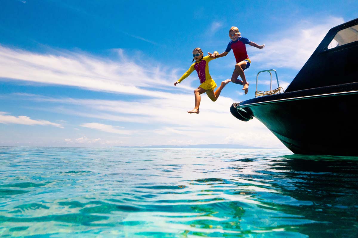Young boy and girl jumping in the water from a boat in the sea of the Amalfi Coast