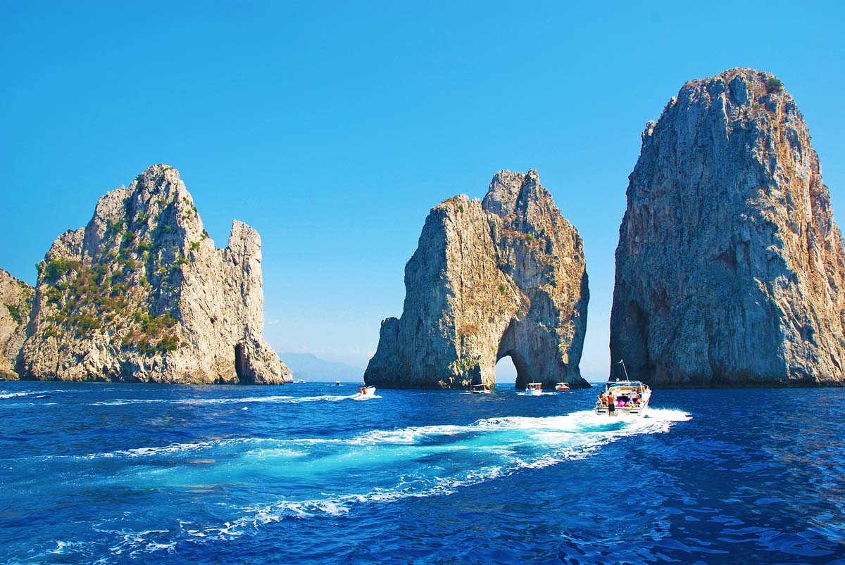 motor boats with the faraglioni rock stacks sailing during a shore excursion from naples